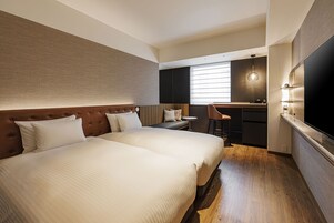A hotel room with a large bed, a small kitchenette, and a seating area with a view of the city.
