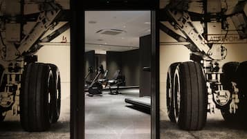 A room with large industrial-style tires, a treadmill, and a mirrored wall.