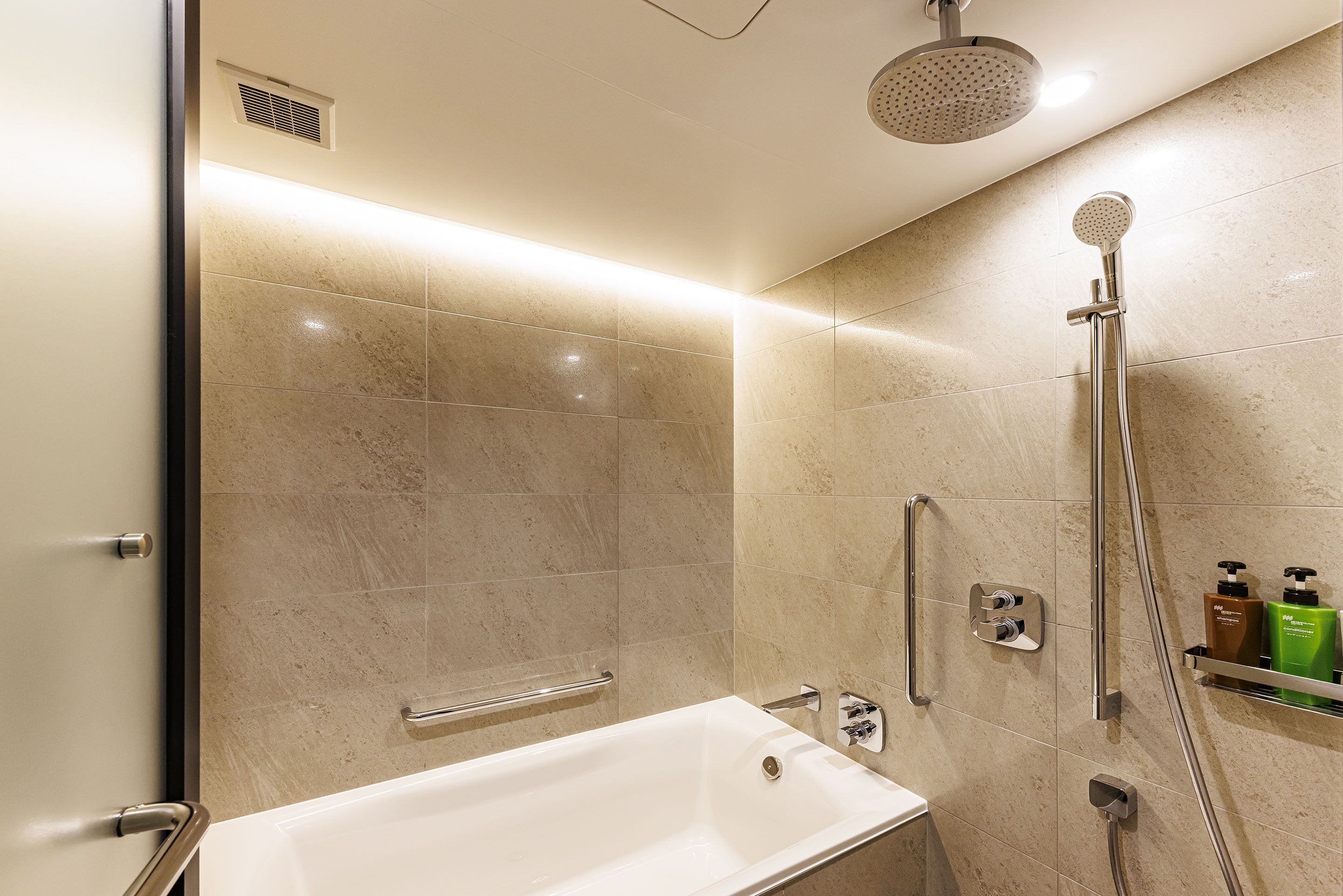 A modern bathroom with a bathtub, a shower, and a handrail.