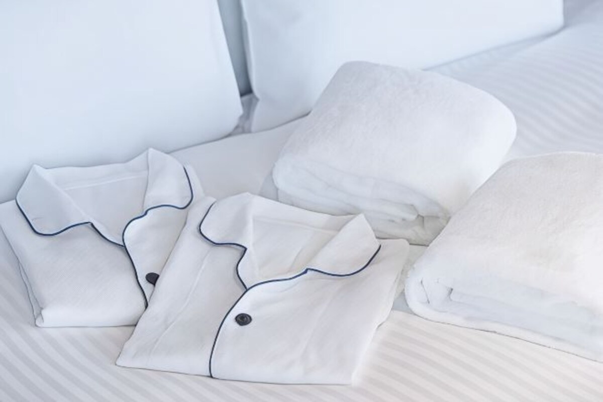 Roupa de cama branca e bem dobrada, com detalhes escuros nas bordas.