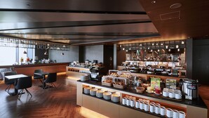 Un bar à petit-déjeuner moderne proposant une variété de plats et de boissons, notamment des machines à café et un assortiment de viennoiseries.