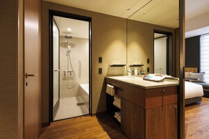 A modern bathroom with a glass-enclosed shower, a wooden vanity with a sink, and a large mirror.