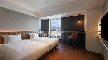 Quarto de hotel moderno com uma cama grande, uma escrivaninha e vista para a cidade.