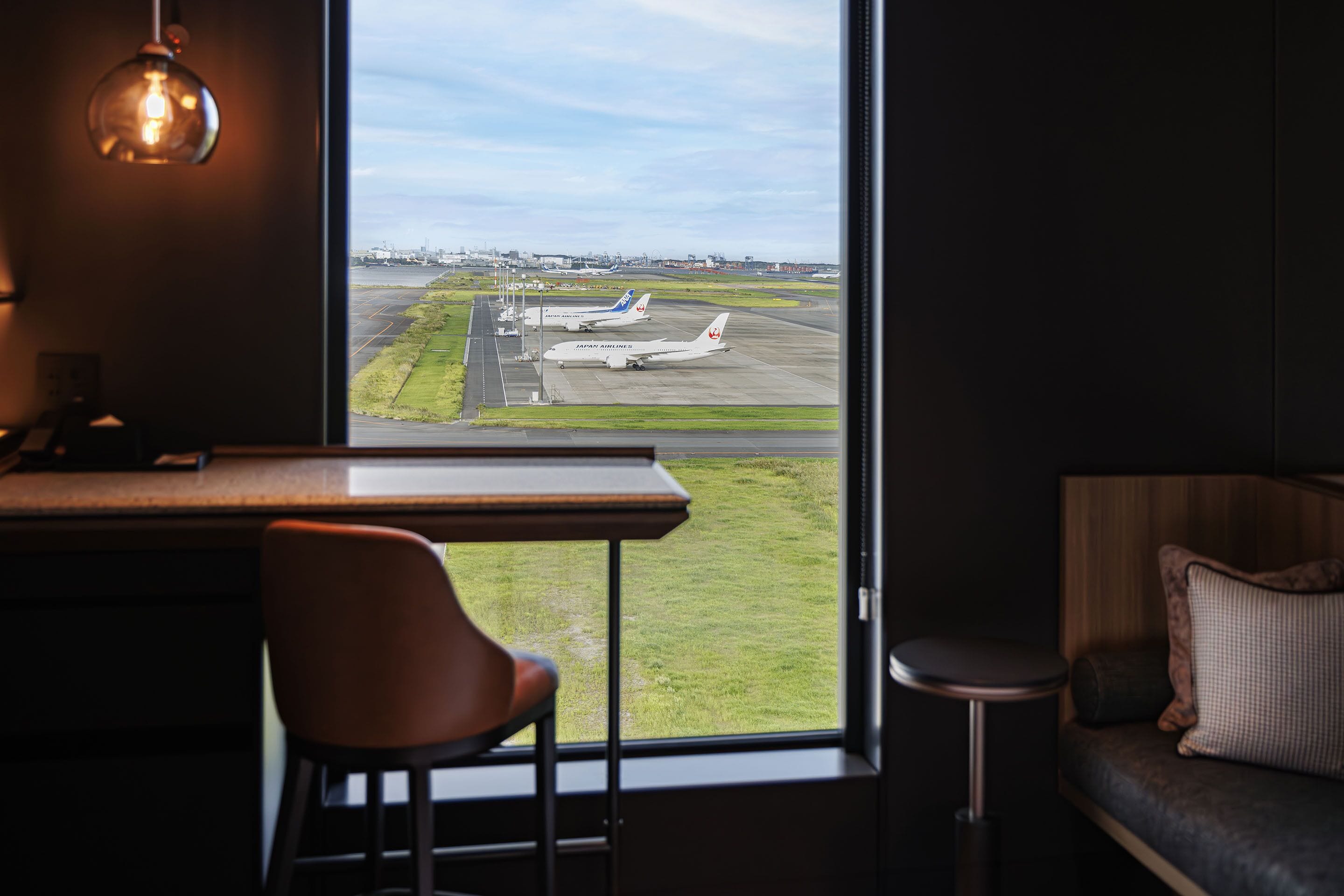 Une chambre dotée d’une grande fenêtre donnant sur un aéroport.