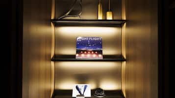 Una estantería con un libro titulado "Night Flight", una escultura de pájaro y dos candelabros.
