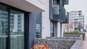 A modern building with large windows, a stone wall, and a sign indicating 'CENTURY 21'. - Modern apartment in the center of Nieuwpoort (Nieuwpoort)