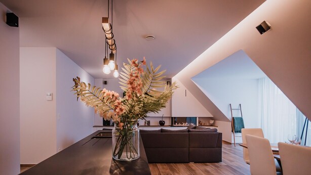 A modern kitchen with a dark countertop, a vase of flowers, and pendant lighting. - Modern apartment in the center of Nieuwpoort (Nieuwpoort)