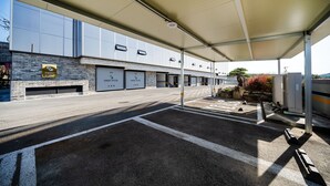 A covered parking area with a brick facade, multiple garage doors, and a clear sky. - SWEET HOTEL (Changnyeong)