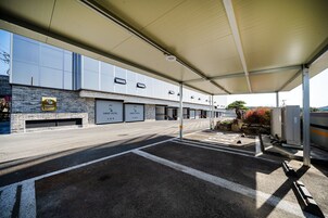Uma área de estacionamento coberta com fachada de tijolos, várias portas de garagem e céu claro.