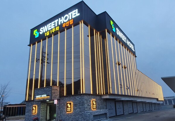 A hotel with a modern design, featuring vertical lighting accents and a prominent sign.