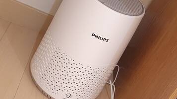 A white Philips smart speaker with a perforated base, placed on a wooden floor near a wall socket.