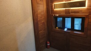 A hotel reception area with a wooden reception desk, a welcome mat, and a fire extinguisher. - SWEET HOTEL (Changnyeong)
