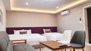 A hotel room with two beds, a sofa, a coffee table, and a chair. - SWEET HOTEL (Changnyeong)