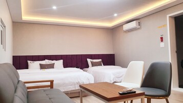 Quarto de hotel com duas camas, um sofá, uma mesa de centro e uma cadeira.