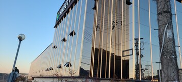 Um edifício moderno com fachada de vidro refletante, linhas verticais e uma placa com a palavra "SWEET".