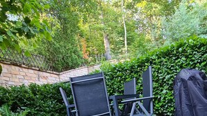 Eine Holzterrasse mit Gartenmöbeln und einem Grill.