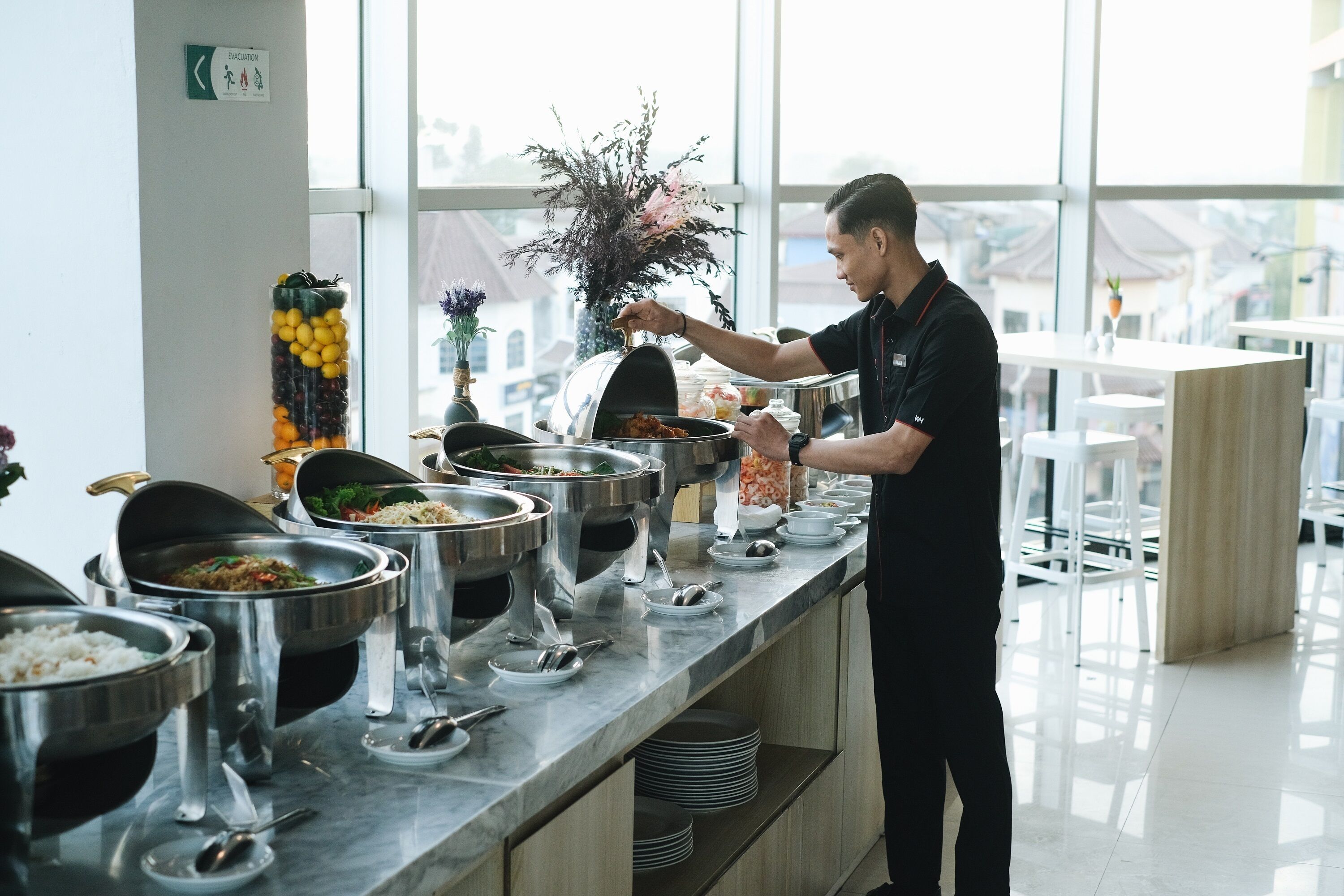 A buffet setup with various food items and a staff member serving.