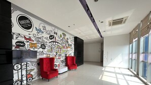 Un vestíbulo moderno con un mural de mapa de la ciudad, asientos rojos y un amplio ventanal que proporciona luz natural.