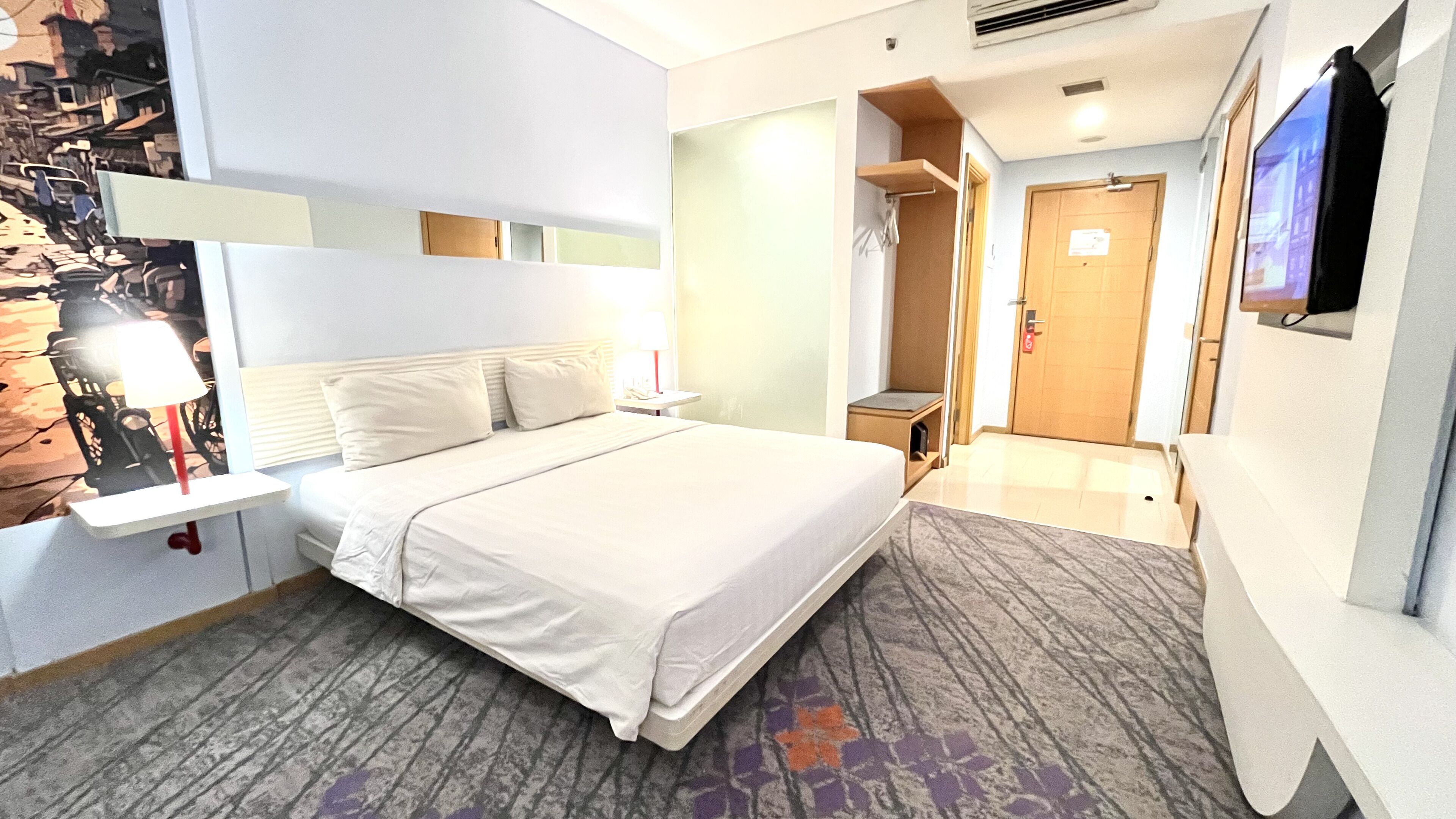 A hotel room with a bed, a desk, a TV, and a bathroom.