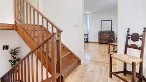 A wooden staircase leading to a room with a herringbone floor, a wooden chair, and a dresser.