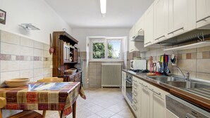 A kitchen with a dining table, cabinets, a window, and a radiator.