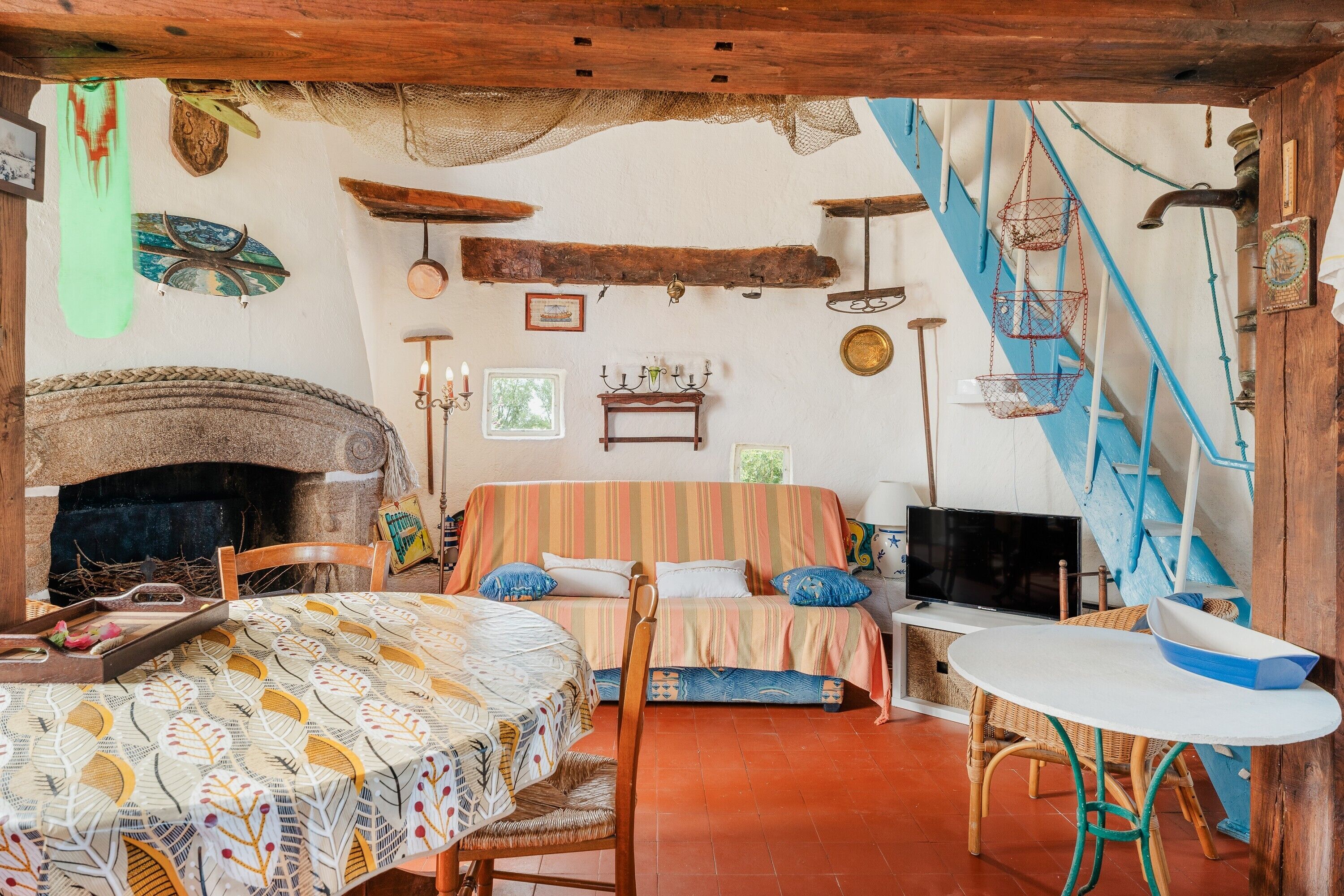 A cozy room with a fireplace, a bed with striped bedding, a television, and a dining table with chairs.