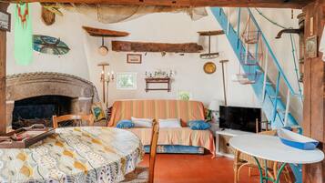 A cozy room with a fireplace, a bed with striped bedding, a television, and a dining table with chairs.