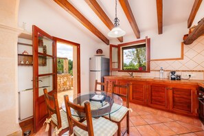 A kitchen with wooden cabinets, a glass dining table, and a view of the outdoors.