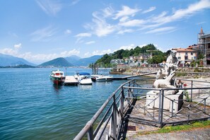 A waterfront view with boats docked, a statue, and buildings in the background.