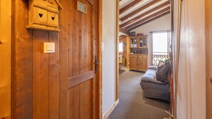 A wooden interior with a door, a small wooden structure, and a sofa in a room with a sloped ceiling. - Ski in/ski Out Holiday Apartment (Crest-Voland)