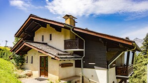 A rustic mountain house with a wooden balcony, a wooden staircase, and a small porch. - Ski in/ski Out Holiday Apartment (Crest-Voland)