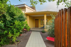 A courtyard with a tiled pathway, a wooden door, and a bench.