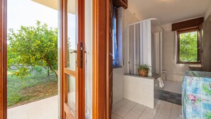 Een badkamer met een douche, een wastafel en een raam.