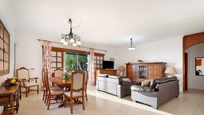 A spacious living room with a dining area, a sofa set, and a television. - Vacation Home 'Biofinca Las Dulces Villa Alma' with Sea View, Pool & Wi-Fi (Guia de Isora)