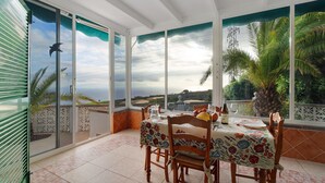 A dining area with a table set for two, a bottle, and a glass on the table. - Vacation Home 'Biofinca Las Dulces Villa Alma' with Sea View, Pool & Wi-Fi (Guia de Isora)