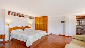 A bedroom with a bed, bedside tables, a wardrobe, a shelf with books, and a bathroom visible through an open door. - 'Biofinca Las Dulces Casa Almita' with Sea View, Private Terrace and Wi-Fi (Guia de Isora)