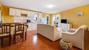 A compact living space with a dining area, sofa, TV, and kitchen. - 'Biofinca Las Dulces Casa Almita' with Sea View, Private Terrace and Wi-Fi (Guia de Isora)