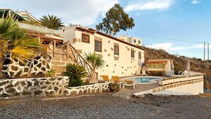 Ein Haus mit Swimmingpool, Steinmauern und Blick auf eine Hügelterrasse.