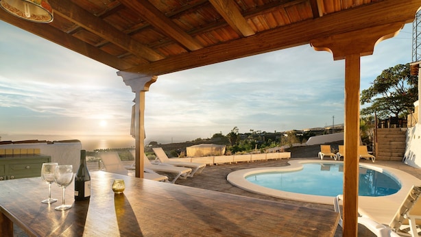 Eine Holzpergola mit Pool und Liegestühlen.