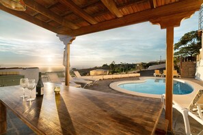 Une pergola en bois avec une piscine et des chaises longues.