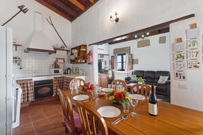 A kitchen with a dining area, a fireplace, and a living room with a couch and plants.