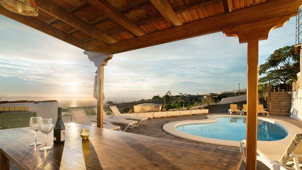 Eine Holzpergola mit Pool und Liegestühlen.