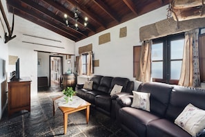 A living room with a leather sofa, a wooden coffee table, and a chandelier.