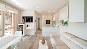 A modern kitchen with a central island, a dining area with a white table and chairs, a beige sofa, and a small decorative gold object on a white pedestal. - Apartment 'Wieser Garda Lake' with Lake View, Wi-Fi and Air Conditioning (Gargnano)
