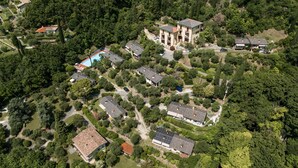 An aerial view of a residential area with multiple houses, a swimming pool, and a large building with a red roof. - Apartment 'Wieser Garda Lake' with Lake View, Wi-Fi and Air Conditioning (Gargnano)