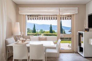Una habitación moderna con comedor, sofá, televisión y vistas a montañas y vegetación.