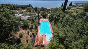 A swimming pool surrounded by lush greenery, with a view of a lake and distant mountains. - Apartment 'Wieser Garda Lake' with Lake View, Wi-Fi and Air Conditioning (Gargnano)