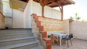 Un escalier menant à un patio couvert, équipé d’une table et de chaises.