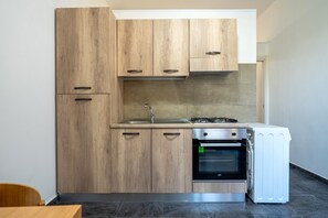 Una cocina con armarios de madera, estufa a gas, horno y refrigerador blanco.
