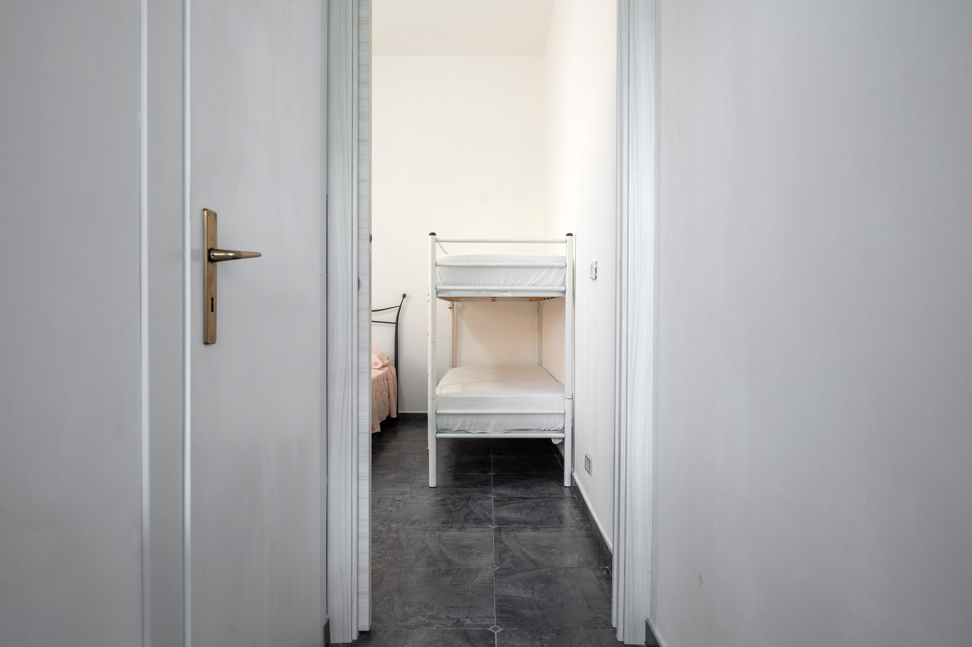 Un couloir étroit avec un lit superposé et une porte dotée d’une poignée.